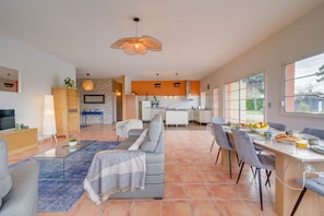 Amplia sala de estar con sofá, mesa de comedor y cocina al fondo.