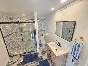 Un baño moderno con cabina de ducha de vidrio, un lavabo blanco y un espejo.