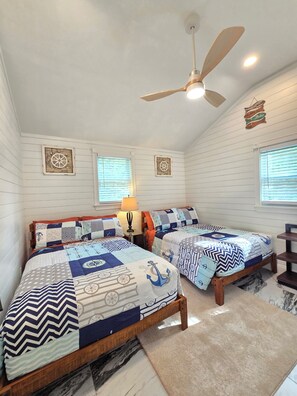 Un dormitorio con dos camas de madera, un ventilador de techo y decoración temática náutica.
