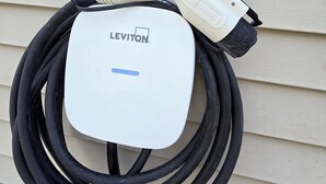 Una caja eléctrica Leviton blanca con un cable negro conectado, montada en una pared color beige.