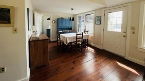 Un comedor con una mesa y sillas de madera, un armario azul y una puerta blanca.