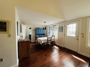 A dining area with a wooden table and chairs, a blue cabinet, and a white door.