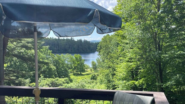 Un mirador con una mesa y una silla, con vistas a un lago y un bosque.