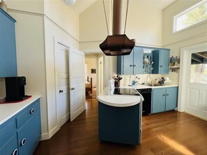 A kitchen with a central island, white cabinets, and a coffee machine.