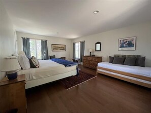 A bedroom with a bed, a dresser, a bedside table, a lamp, a mirror, and a painting on the wall.