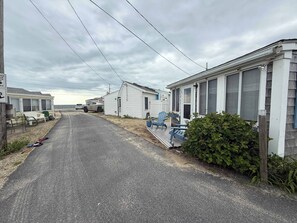 Eine Reihe von Mobilheimen, getrennt durch eine asphaltierte Straße, jedes mit einer Veranda und Sitzgelegenheit im Freien.