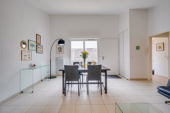 A dining area with a glass table, chairs, and a vase of flowers.