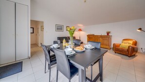 A dining area with a table set for four, a sofa, a cabinet, and a lamp.