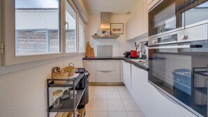 A modern kitchen with a Bosch oven, a small island with jars, and a window with a view of a fence.