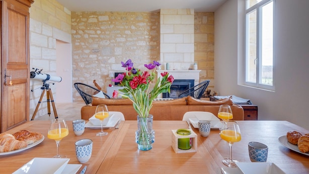 Een eethoek met een houten tafel, ontbijtartikelen en een bloemenvaas.