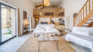 Un espacioso dormitorio tipo loft con una cama grande, una mesa de madera, un balcón y una escalera.
