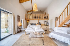 Un'ampia camera da letto mansardata con un letto grande, un tavolo in legno, un balcone e una scala.
