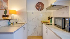 A compact kitchen with a sink, microwave, and a wall-mounted fan.