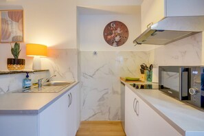 A compact kitchen with a sink, microwave, and a wall-mounted fan. - Wine Lodge - Two Bedroom Apartment, Sleeps 4 (Libourne)