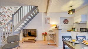 A modern kitchen with a dining table, chairs, and a staircase leading to another level.