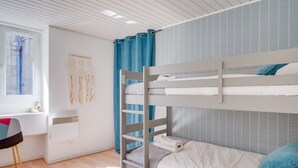 A bunk bed room with a desk and a window.