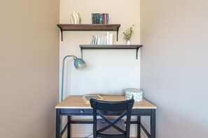 Ein Schreibtisch mit Stuhl, einer Lampe und Bücherregalen darüber.