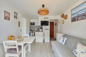 A compact living space with a kitchenette, dining area, and a sofa with patterned cushions. - Le Martrois - À 200 m de la plage (Villers-sur-Mer)