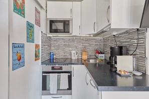 A modern kitchen with white cabinets, a microwave, a coffee machine, and a kettle. - Le Martrois - À 200 m de la plage (Villers-sur-Mer)