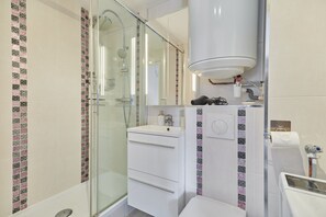A modern bathroom with a glass shower enclosure, a white vanity with a mirror, and a toilet. - Le Martrois - À 200 m de la plage (Villers-sur-Mer)