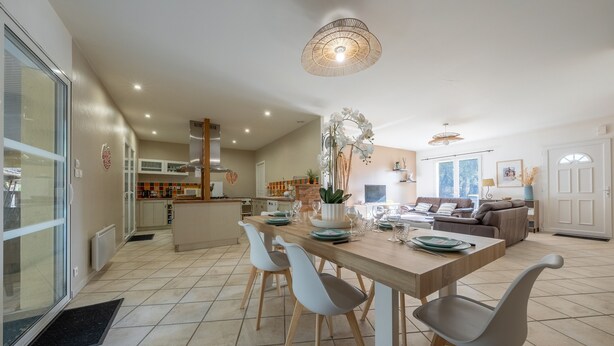 A spacious dining area with a wooden table, white chairs, and a central decorative plant. - Rosie - Jolie maison avec terrasse et piscine (Le Verdon-sur-Mer)