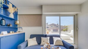 A living room with a blue sofa, a coffee table, and a view of the outside.