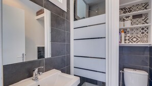 A bathroom with a white sink, a mirror, a toilet, and patterned tiles.