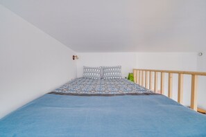 Une chambre à coucher avec un lit, une tête de lit en bois et un luminaire fixé au mur.