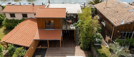 A two-story house with a wooden deck, a swimming pool, and a view of the water.