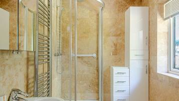 A modern bathroom with a glass-enclosed shower, a white sink, and a cabinet.