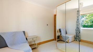 Une chambre à coucher avec un lit, une table de chevet, un miroir et une fenêtre donnant sur un paysage verdoyant.