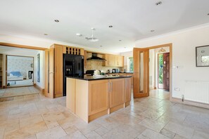 A modern kitchen with wooden cabinets, a black refrigerator, and a central island. - The Limes Bungalow (Market Rasen)