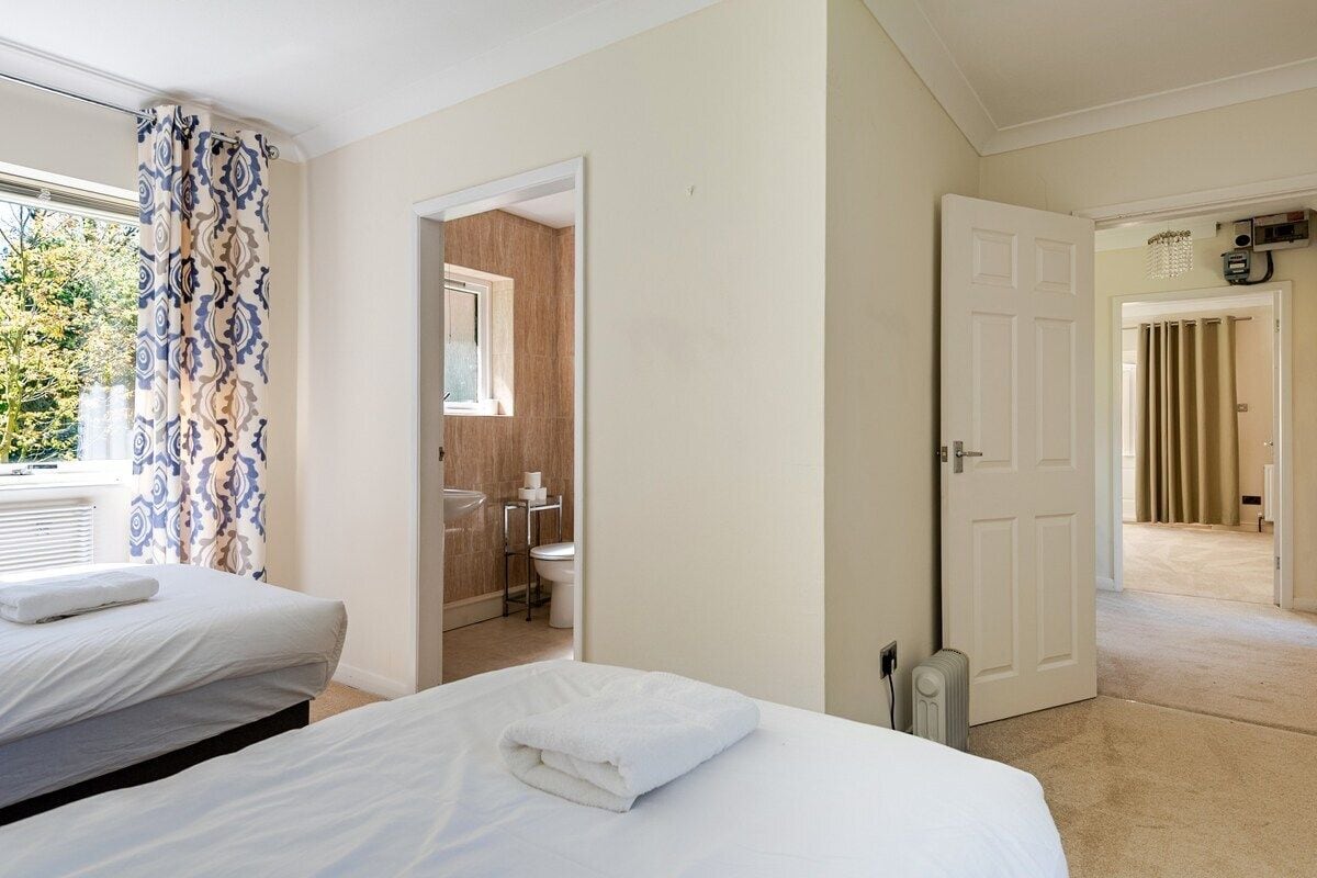 A hotel room with two beds, a bathroom, and a view of the outdoors.