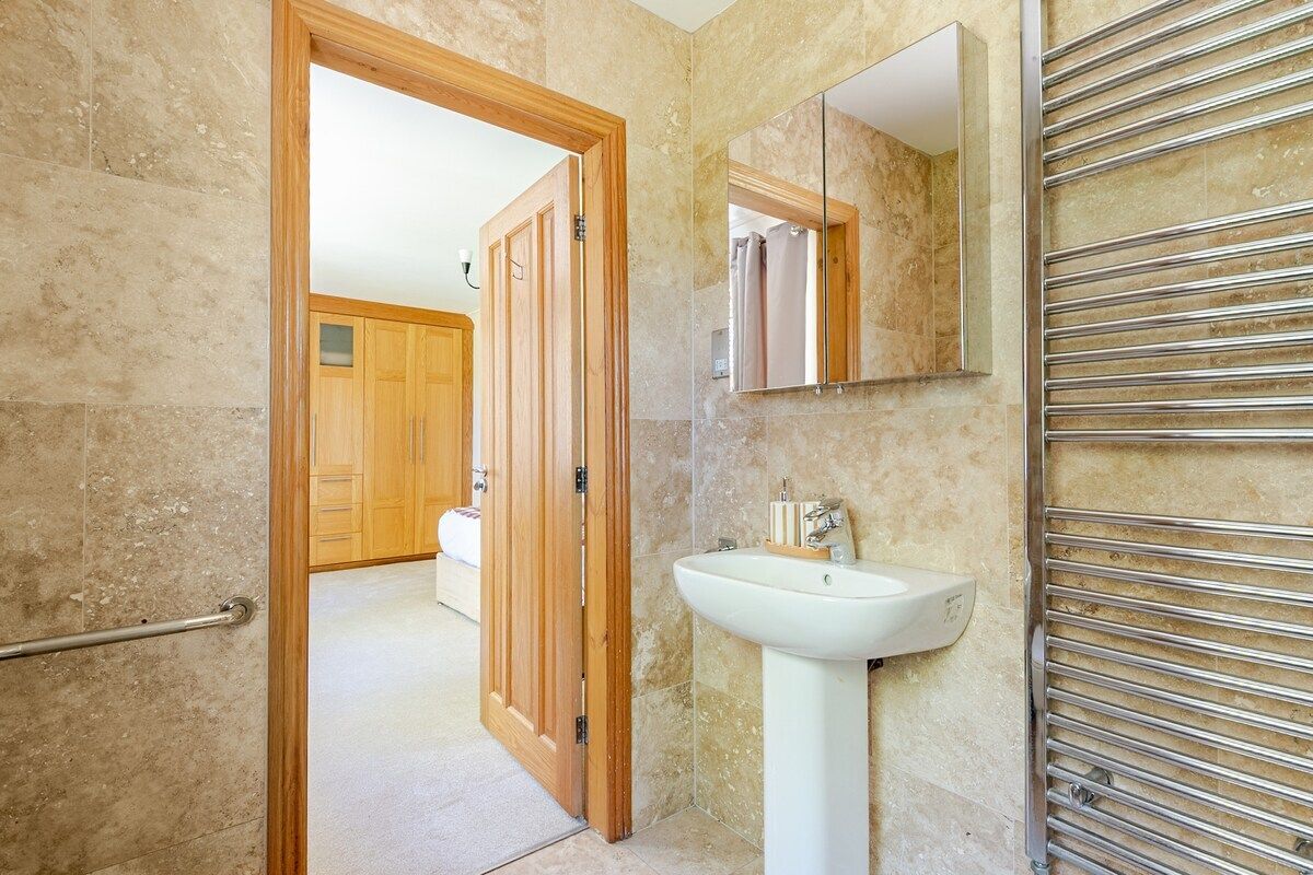 A bathroom with a wooden door, a white sink, a mirror, and a towel rack.