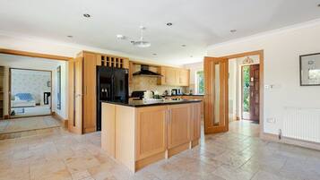 A spacious kitchen with a central island, wooden cabinets, and a black refrigerator.