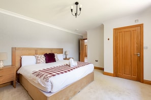 Habitación de hotel con una cama grande, una mesita de noche, una lámpara, una puerta de madera y un candelabro.