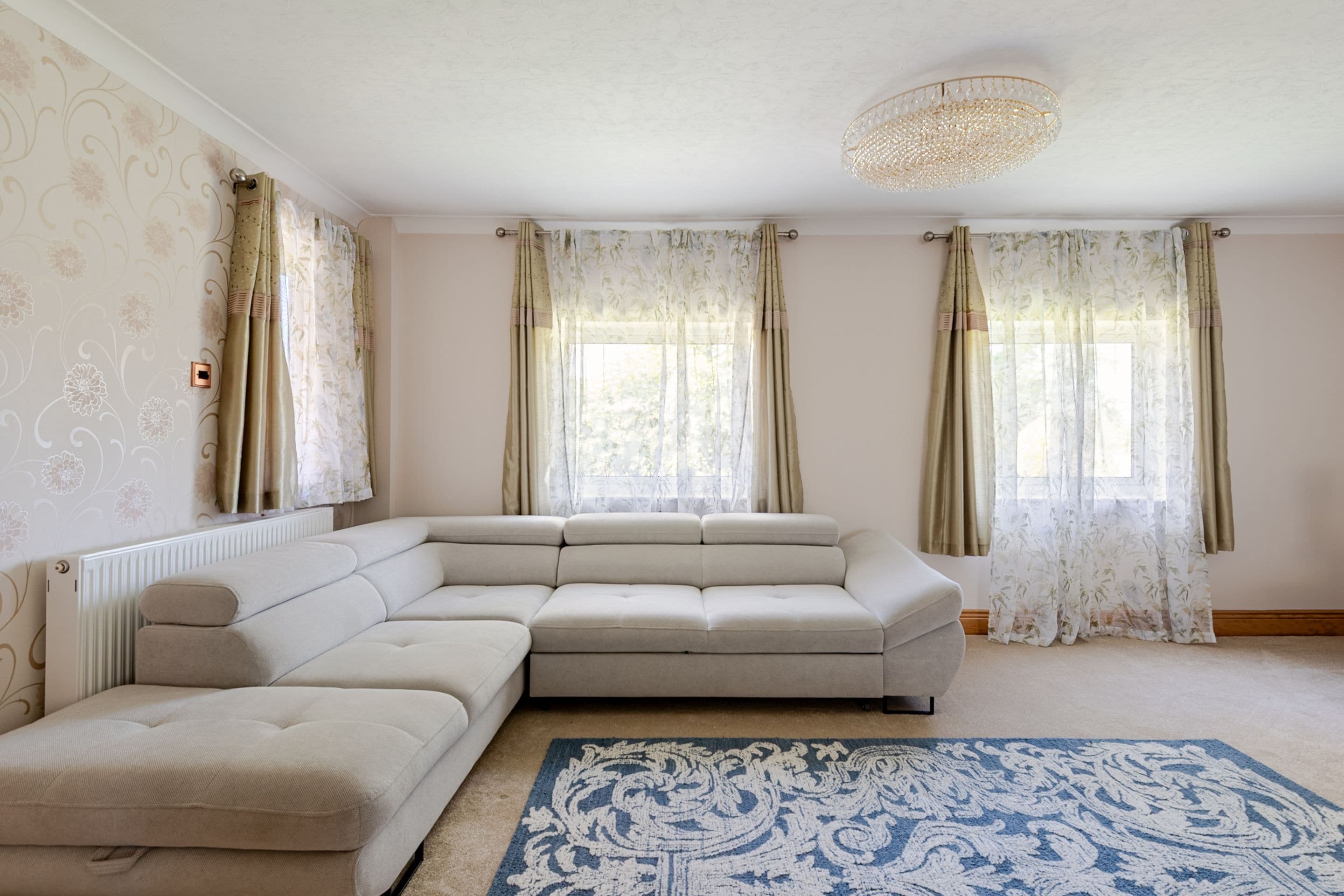 A living room with a sectional sofa, a patterned rug, and a ceiling light fixture.