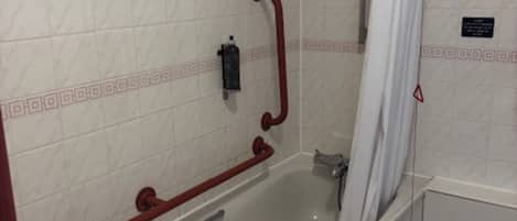 Un baño con bañera, ducha y barandilla.