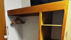 A wooden wardrobe with three drawers and a hanging space, located in a corner of a room with a dark wooden floor. - Monifieth Farm Hotel (Dundee)
