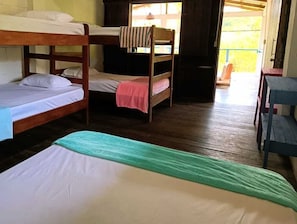 Una habitación con literas, suelo de madera y ventana con cortinas.
