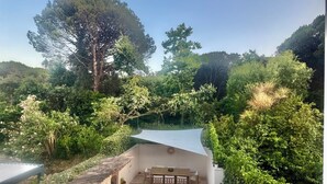 A rooftop terrace with a view of a forested area, a white wall, and a table with chairs. - House near downtown Saint-Tropez (Gassin)