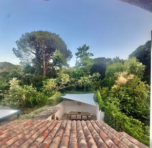 A rooftop terrace with a view of a forested area, a white wall, and a table with chairs. - House near downtown Saint-Tropez (Gassin)