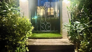 A gated entrance with a metal gate, a stone pathway, and lush greenery. - House near downtown Saint-Tropez (Gassin)
