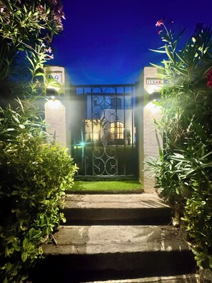 A gated entrance with a metal gate, a stone pathway, and lush greenery. - House near downtown Saint-Tropez (Gassin)