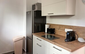 Eine Küchenzeile mit einem Edelstahlkühlschrank, einem Toaster und einer Kaffeemaschine auf der Arbeitsfläche.