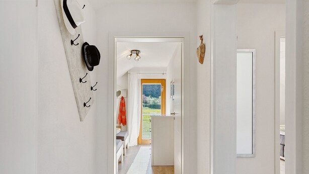 A hallway with a white door, a mirror, and a coat rack with hats. - Dog-Friendly Holiday Apartment with 2 Balconies and Wi-Fi (Bräunlingen)