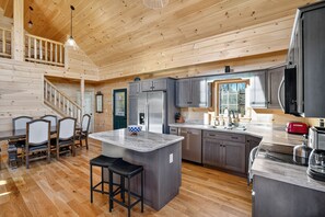 A spacious kitchen with wooden floors, a central island, and a dining area with chairs. - Peaceful Lakefront Cabin w/ Private Dock and Kayaks (Athens)