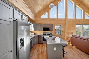 A modern kitchen with a central island, stainless steel appliances, and wooden flooring. - Peaceful Lakefront Cabin w/ Private Dock and Kayaks (Athens)