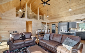 A spacious living area with leather sofas, a dining table, and a kitchen with grey cabinets. - Peaceful Lakefront Cabin w/ Private Dock and Kayaks (Athens)