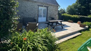 Una casa in pietra con patio piastrellato, mobili da esterno e un giardino con erba.